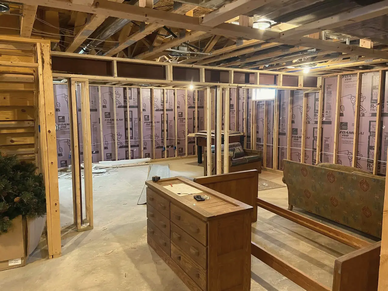 A basement being framed, with new stud walls in front of pink foam insulation