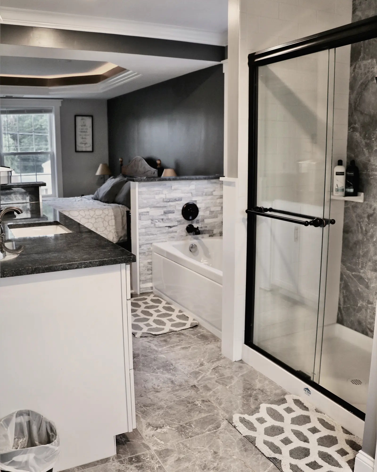 A primary bathroom with a white vanity, a soaking tub in a stacked-stone surround and a glass-door shower