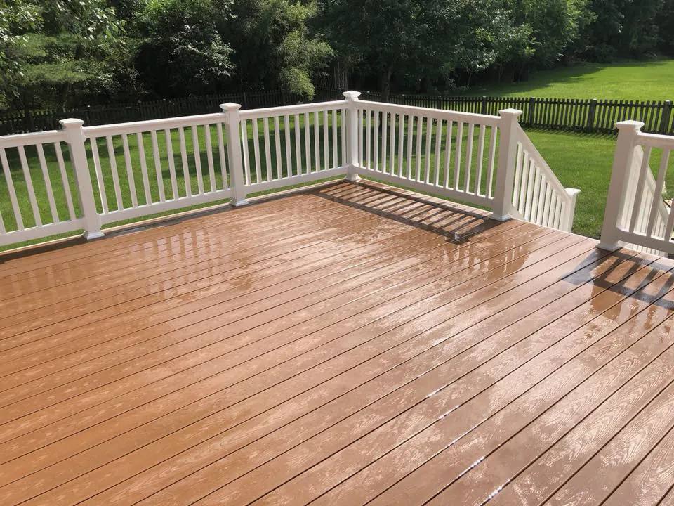 Reddish-brown composite deck boards, wet after rain, behind white vinyl railings
