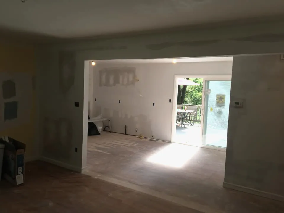 A wide opening where a bearing wall has been taken out between a kitchen and a family room, with fresh drywall patches