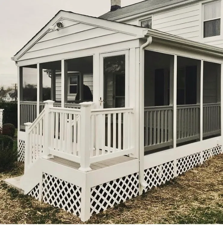 A white gabled screened porch with steps down to the yard and a lattice skirt