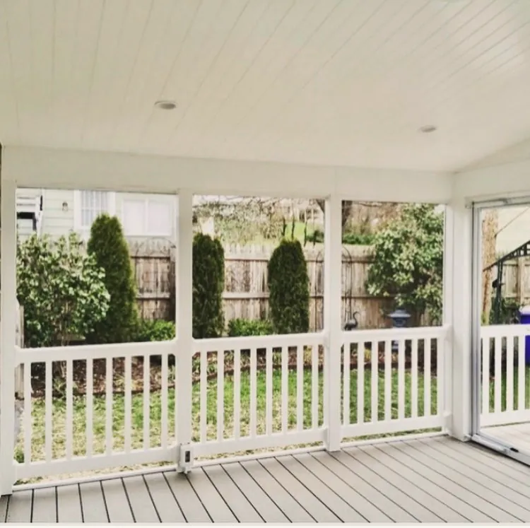 Inside a screened porch with a white ceiling and recessed lights, white railings and a gray floor
